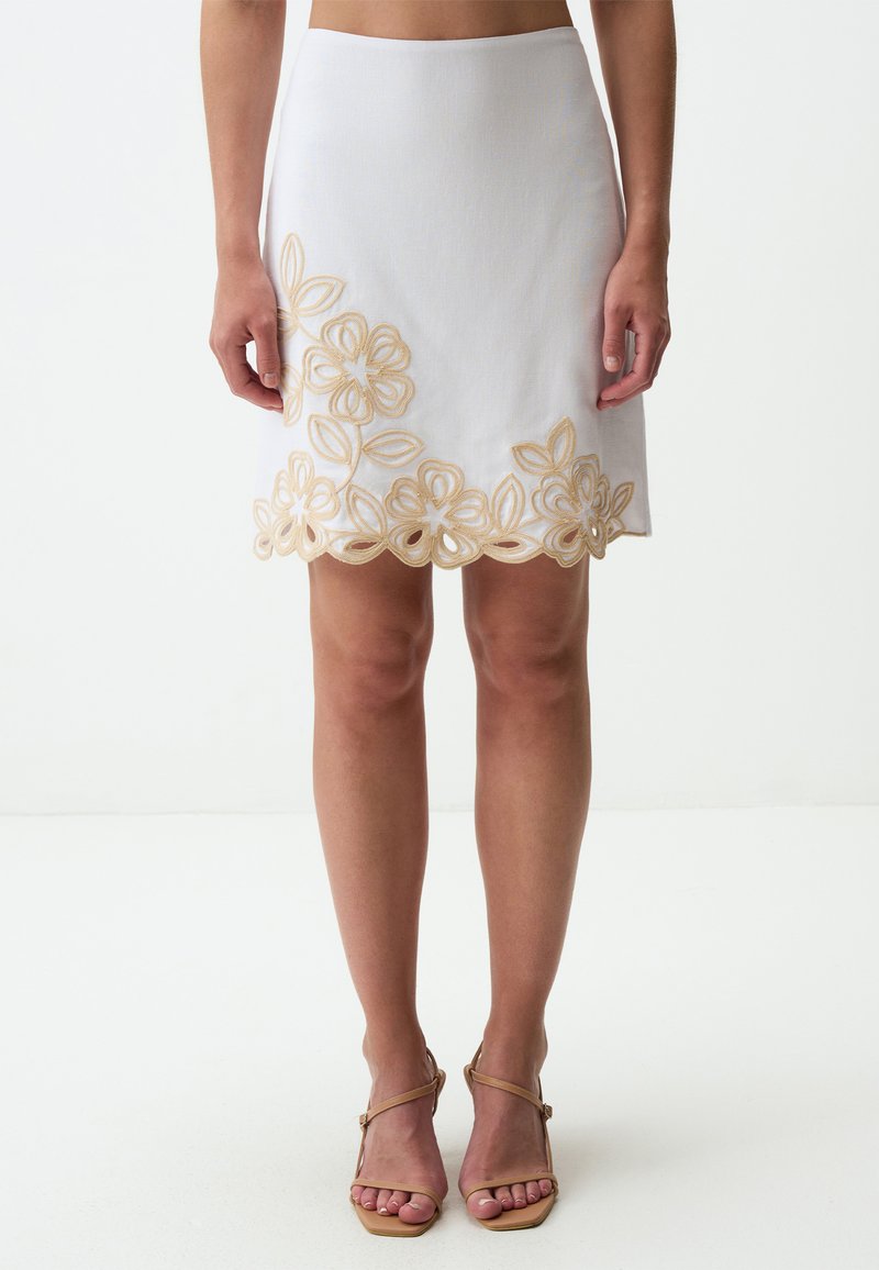 Gonna bianca con design floreale ricamato in oro sull'orlo, caratterizzata da una silhouette aderente e un tessuto liscio e strutturato.