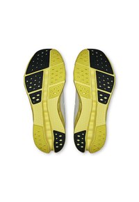 Les semelles des chaussures de sport affichent une base jaune avec des accents noirs et des motifs texturés, conçus pour l'adhérence et la flexibilité.