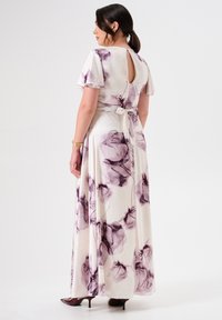 Maxikleid aus leichtem Stoff mit lilafarbenem Blumenmuster auf einem cremefarbenen Hintergrund. Es hat kurze schwingende Ärmel und ein Bindeband in der Taille.