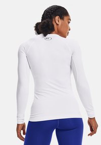 Weißes, langärmliges Sportoberteil mit tailliertem Design, glatter Textur und rundem Logo am Ausschnitt. Das dehnbare Material sorgt für Flexibilität.