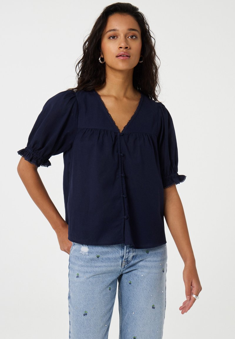 Dunkelblauses kurzärmliges Blusenshirt mit V-Ausschnitt, Knopfleiste und Rüschensäumen. Der leichte Stoff hat eine feine Textur.