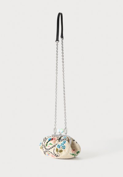 Petit sac en tissu beige avec broderies florales colorées, armature en métal argenté et longue bandoulière chaîne argentée avec un coussinet d’épaule en cuir noir.