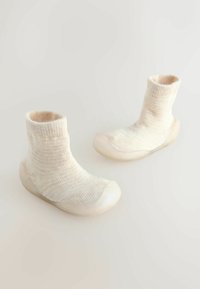 Gestrickte Socken in cremefarbener Farbe, mit einem strukturierten, gerippten Muster und einer glatten, hellen, abgerundeten Gummisohle für Griffigkeit und Flexibilität.