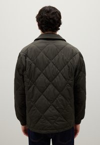 Giacca trapuntata verde scuro con colletto, caratterizzata da un motivo a diamante, maniche lunghe e polsini elasticizzati. Design semplice e funzionale.