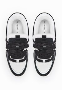 Czarno-białe sneakersy z gładką skórzaną cholewką, teksturowanymi akcentami z tkaniny, wyraźnymi sznurowadłami oraz logo nadrukowanym na wkładce.