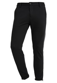 Schwarze Hosen aus einem glatten Stoff, mit schmaler Passform, seitlichen weißen Streifen und aufgerollten Säumen mit Reißverschlüssen am Abschluss.