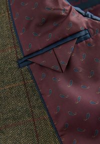 Brunt fiskbensmönster av tyg med en vinröd, mönstrad underlägg som har blå accenter. Kantad med en marinblå kant. Lättviktig och texturerad.