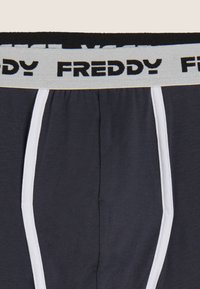 Boxer grigi scuro con una fascia in vita nera con il marchio bianco "FREDDY". Il tessuto ha una texture liscia con dettagli in bianco.