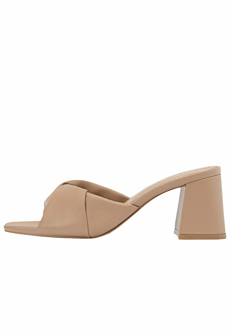 Sandales à talons blocs beige avec une finition en cuir lisse, présentant un design noué au niveau des orteils et un dos ouvert pour un enfilage facile.