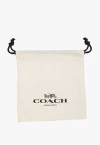 Kerchief tas berbahan katun berwarna krim dengan huruf hitam. Menampilkan logo "COACH NEW YORK" dan desain kereta hias. Tekstur halus.