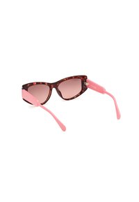 Gafas de sol estilo gato con montura de carey, patillas rosas y lentes degradados. Diseño ligero de plástico con un acabado suave.