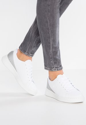 Sneaker bianca con tomaia in pelle liscia, dettagli grigi sul tallone e design minimalista con chiusura con lacci.