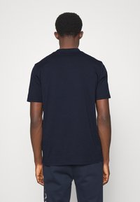 Dark navy blue short-sleeve t-shirt, cotton material, round collar, plain design, minimal stitching detail. Worn with matching dark pants.