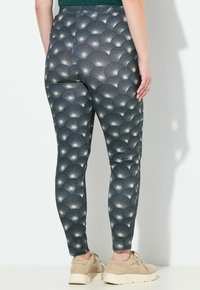 Leggings gemaakt van rekbaar materiaal, met een donkere achtergrond en een herhalend waaierpatroon in grijs en wit, in een nauwsluitende pasvorm.