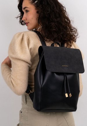 Black leather backpack with a flap closure, featuring gold hardware accents and two adjustable straps. The material has a smooth texture.