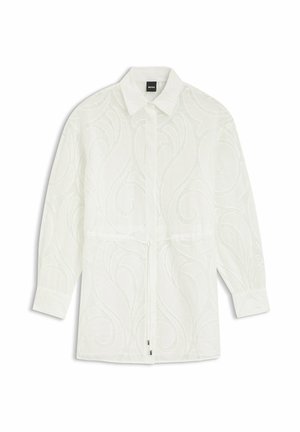 Blusa blanca de manga larga con un sutil patrón texturizado en espiral, cuello con solapa, cierre con botones y cintura ajustable con cordón.