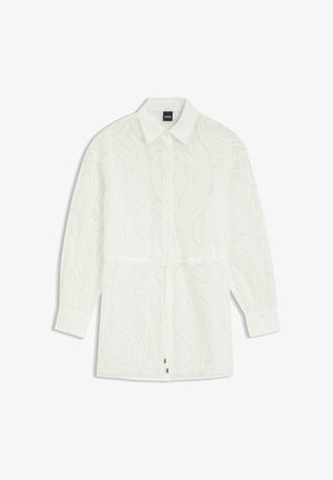 Blusa blanca de manga larga con un sutil patrón texturizado en espiral, cuello con solapa, cierre con botones y cintura ajustable con cordón.