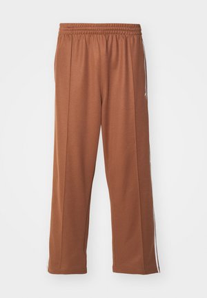 Pantalones deportivos marrones de corte holgado, con cinturilla elástica y franjas laterales blancas, fabricados en un tejido suave y liso.
