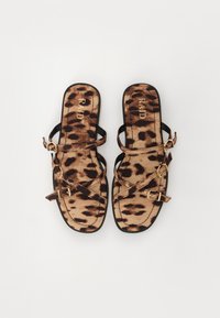 Sandales plates à imprimé léopard avec des brides noires et des boucles dorées. Elles sont dotées d'une semelle intérieure rembourrée et d'un design ouvert, offrant une silhouette élégante.
