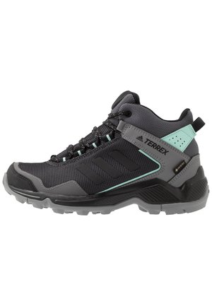 Zwart-grijze Adidas Terrex mid-top wandelschoen met mintkleurige accenten, veters aan de voorkant en een gestructureerde rubberen zool voor grip buiten.
