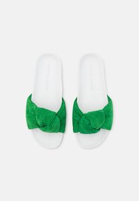 Sandales à plateforme en daim vert avec un accent noué. Les semelles sont blanches, avec une texture lisse et un design minimaliste.