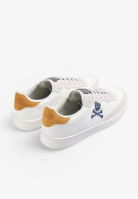 Witte leren sneakers met grijze suède accenten en een tan hielpatch met reliëftekst. Blauwe geborduurde doodskop en gekruiste botten ontwerp.