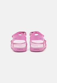 Las sandalias rosa, adecuadas para el agua, cuentan con tiras ajustables, una plantilla texturizada y una suela de goma duradera con un patrón en forma de ola. Branding de "GEOX" en el talón.