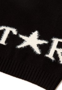 Černá pletená čepice s bílým huňatým designem hvězdy a skriptovým textem, s podrobným ribbovaným manžetem pro pohodlné nošení.