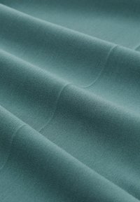 Tissu doux et texturé de couleur teal atténuée, présentant des plis subtils et une surface lisse, idéal pour les vêtements ou les textiles d'intérieur.