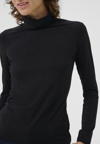 Svart långärmad turtleneck-tröja i ett mjukt material, med en figurnära design och hög krage, samt sömlös konstruktion.