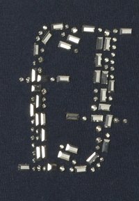 Marineblauw stof met een gestructureerd ontwerp met zilveren strass-steentjes die zijn gerangschikt in een gestileerde letter 'F', met verschillende vormen en maten.