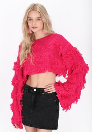 Roze cropped sweater met franjes, lange mouwen en textuurcontrasten, gecombineerd met een hoge taille zwarte spijkerrok.