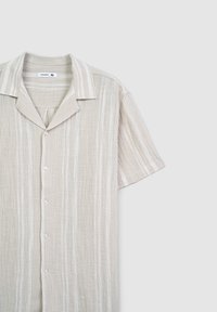 Maglietta a maniche corte beige chiaro con righe bianche verticali. Realizzata in un tessuto testurizzato, presenta un colletto a punta e chiusura con bottoni. Taglia XL.