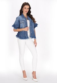 Jeansjacka med fransade kanter, korta volangärmar, knäppning med knappar och två framfickor, kombinerad med vita skinny jeans och klackar.