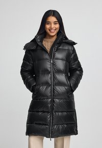 Czarna kurtka puchowa o błyszczącej powierzchni, z zamkiem błyskawicznym, wysokim kołnierzem i dużymi kieszeniami. Posiada pikowaną strukturę i lekko taperowany pas.