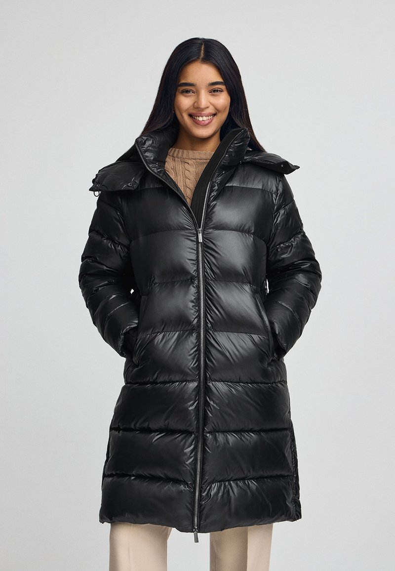 Czarna kurtka puchowa o błyszczącej powierzchni, z zamkiem błyskawicznym, wysokim kołnierzem i dużymi kieszeniami. Posiada pikowaną strukturę i lekko taperowany pas.