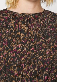 Robe noire avec un col plissé, présentant un motif abstrait marron et rose sur l'ensemble. Tissu doux avec un design fluide.