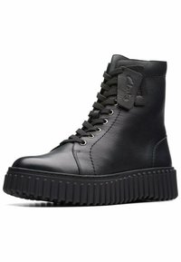 Botas de cuero negro hasta el tobillo con punta redonda, cordones en la parte delantera y suela de goma negra texturizada con surcos verticales. Acentuadas con una etiqueta de marca.