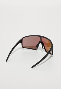 Lunettes de sport avec une monture noire, verres teintés rose, forme rectangulaire large et branches texturées noires pour une prise optimale.