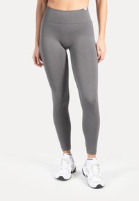 Leggings grigi a vita alta realizzati in materiale elasticizzato, caratterizzati da una texture liscia e un design aderente che si adatta al corpo.