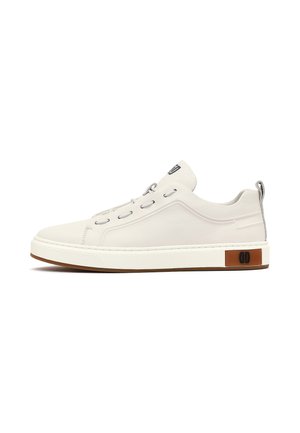 Witte lage sneaker met minimale stiksels, zilveren veteroogjes, een bruine logopatch nabij de zool en een treklus bij de hiel.