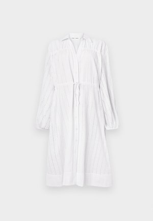 Valge pikkade varrukatega kleit, millel on nööbiga ees, sidumisvöö, silmadega muster ja kokku kogutud varrukad. Sile tekstuur ja lõdva lõikega.