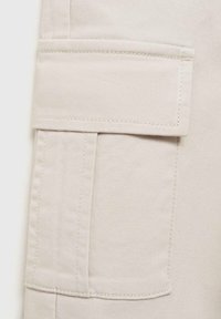 Beige cargobroeken met een patchzak aan de zijkant, gemaakt van een stevige katoenen stofmix. Kenmerken zijn zichtbare stiksels en een gladde textuur.