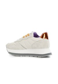Zapatillas de ante y cuero de color gris claro con cordones naranjas, forro púrpura y un acento reflectante metálico en el talón. Presenta una suela blanca gruesa.
