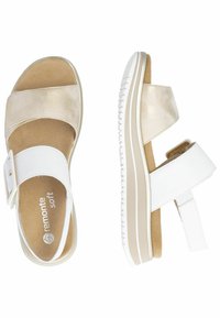 Beige und weiße Sandalen mit zwei Riemen, einer strukturierten Wildlederoberfläche, verstellbarem Riemen und gepolstertem Fußbett auf einer leichten, gerippten Sohle.