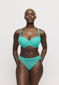 Turkos spetsbehå och matchande höga trosor. Paneldesign med ett subtilt blommönster och slät textur. Justerbara axelband.
