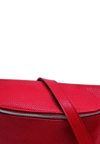 Sac à main en cuir rouge avec une surface texturée, doté d'une fermeture éclair et d'une longue sangle pour le transport.