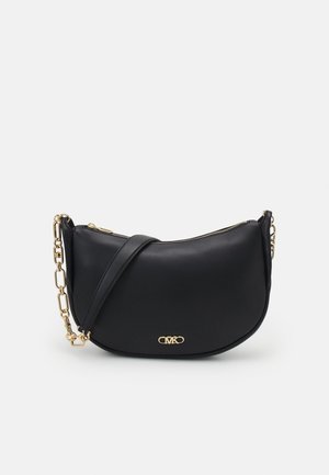 Czarna torebka w kształcie półksiężyca z złotym logo MK, złotym łańcuchem i skórzanym paskiem oraz zamknięciem na zamek błyskawiczny na białym tle.