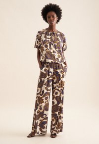 Completo stampato a due pezzi realizzato in tessuto leggero. La parte superiore ha un collo rotondo e maniche corte, mentre i pantaloni sono a gamba larga con un motivo floreale blu e giallo.