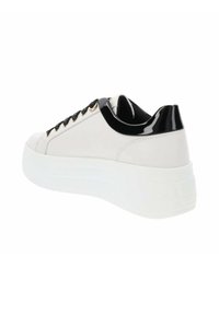 Zapatilla de cuero blanca con talón de charol negro y punta redonda. Presenta cordones negros y detalles en dorado en los ojales. Suela blanca gruesa.